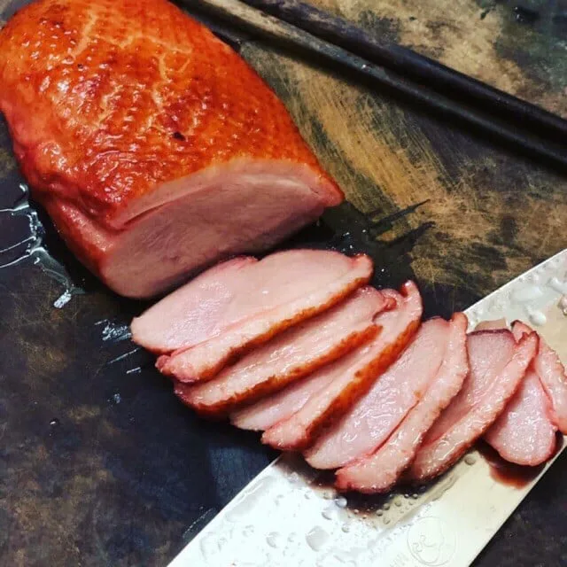 Lườn ngỗng hun khói được thái lát mỏng nghiêng trên thớt gỗ cạnh con dao